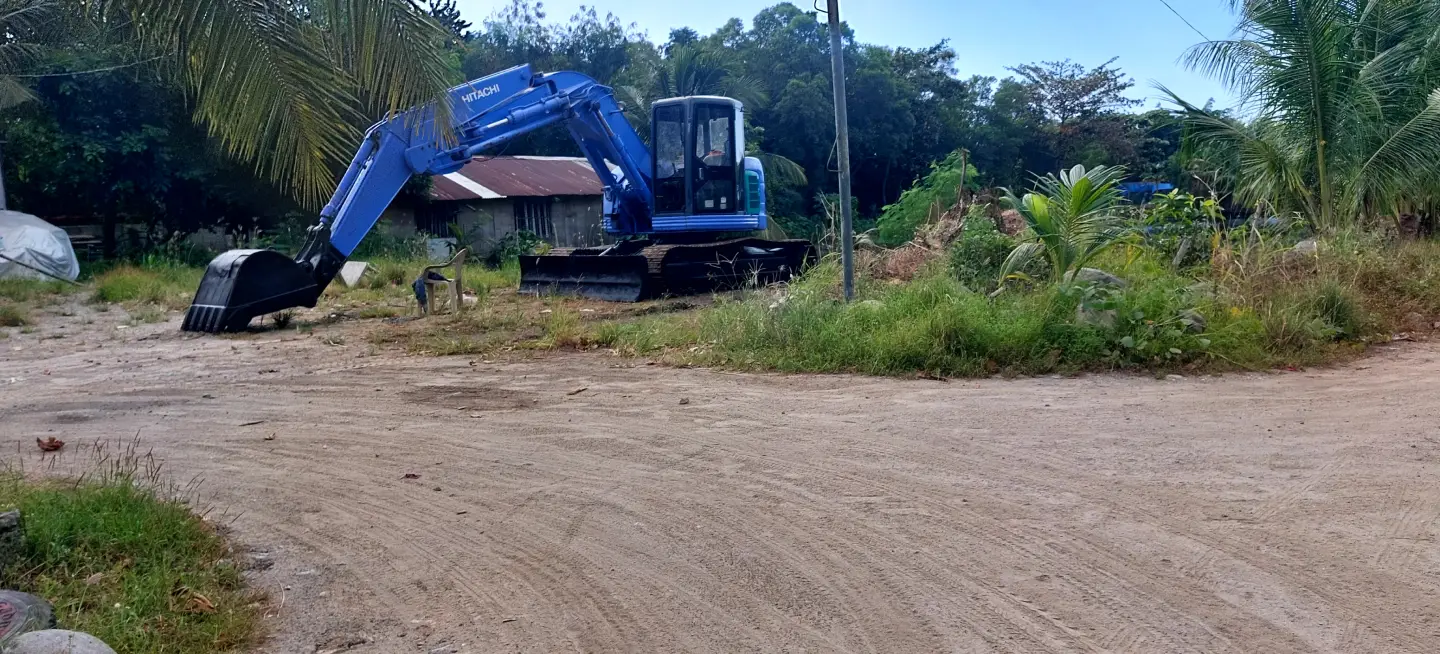 Tracks on the ground lead to a large blue backhoe in the background