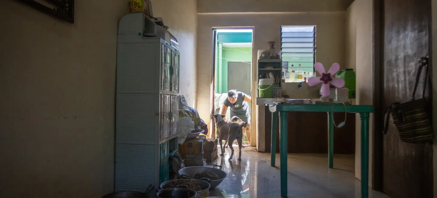 Laarni is greeted by her dog as she enters her house